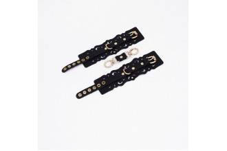 Черные кожаные наручники с узорами и золотистой фурнитурой